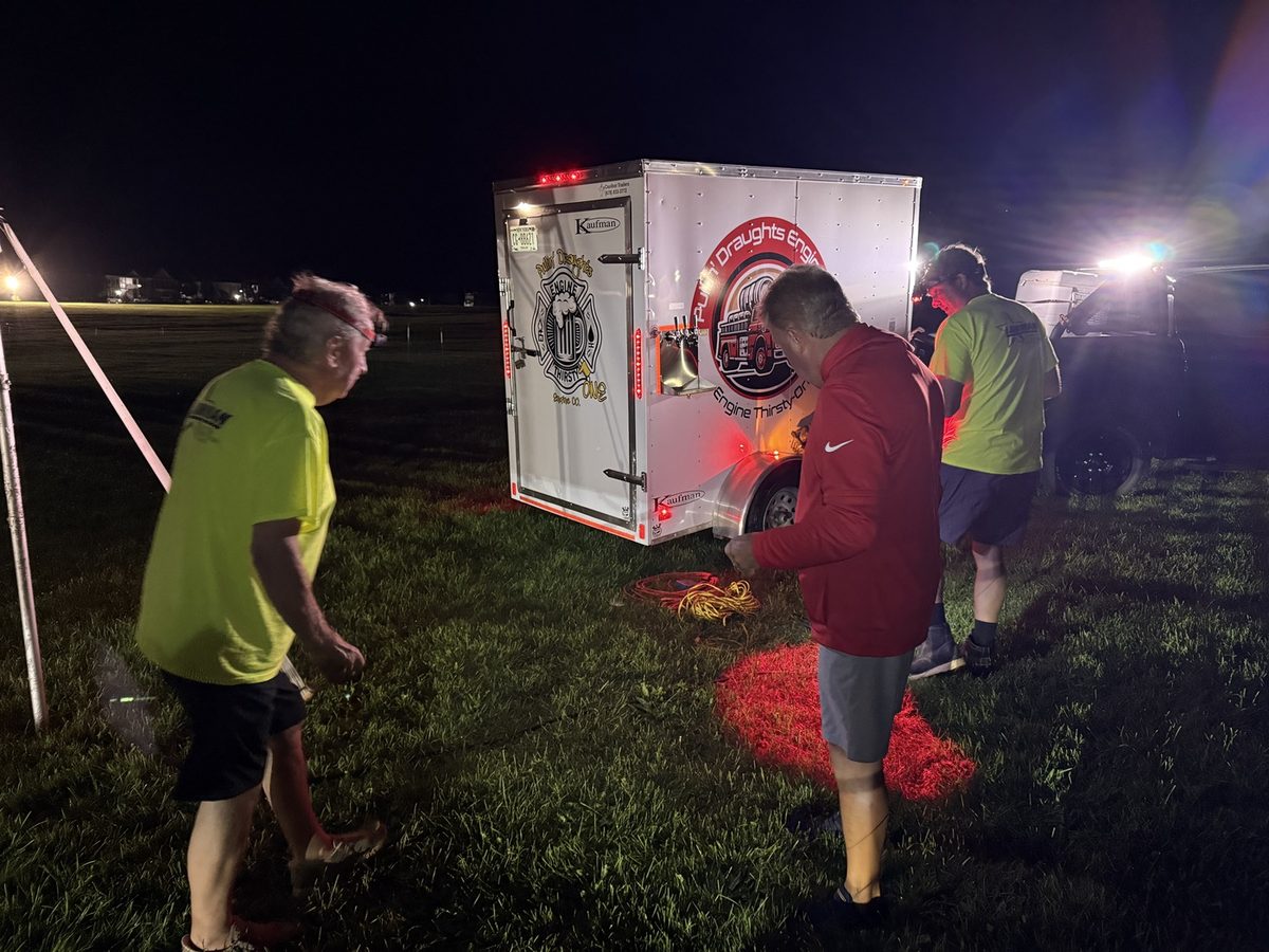 Volunteers unloading gear by floodlight before dawn