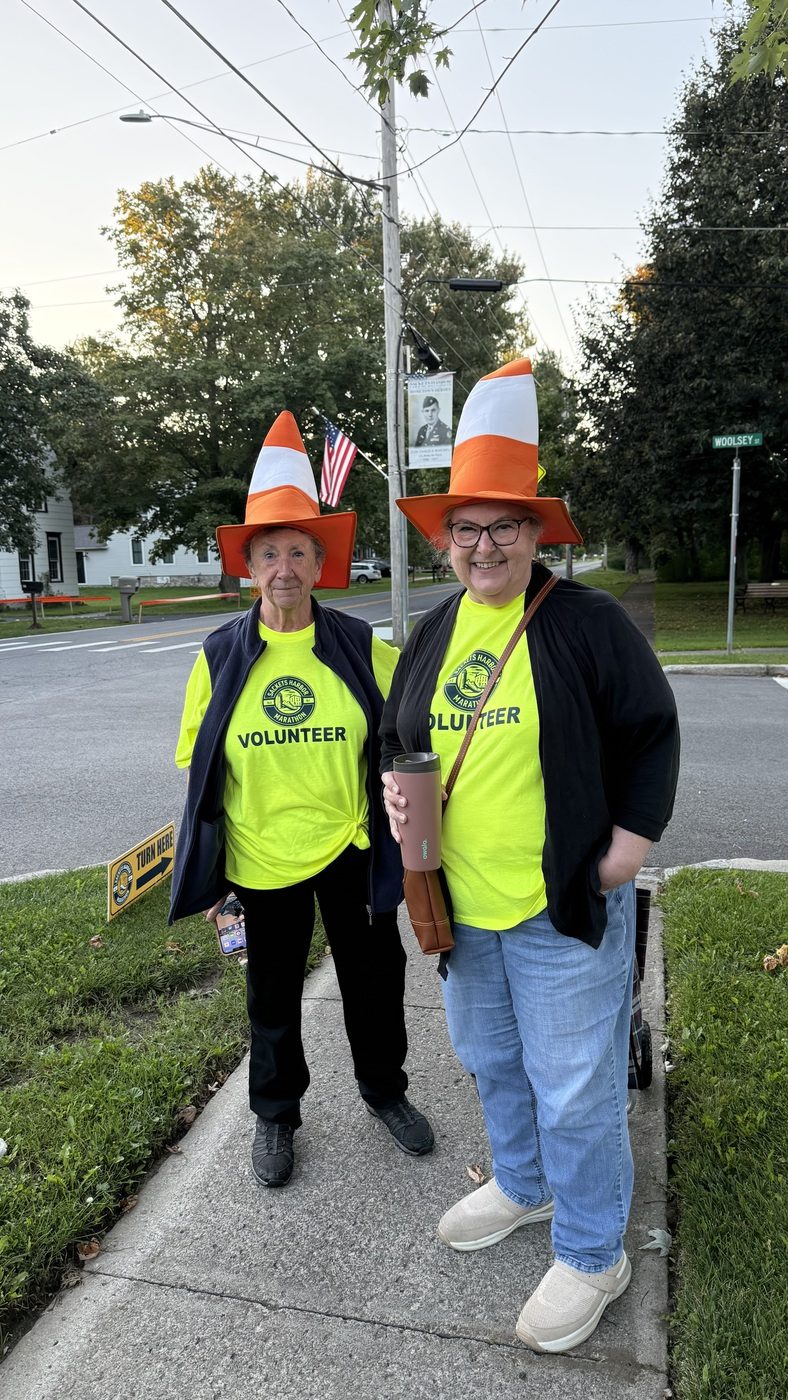 Two volunteers in cone hats at a course corner